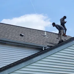 Two roofers working on a shingle roof