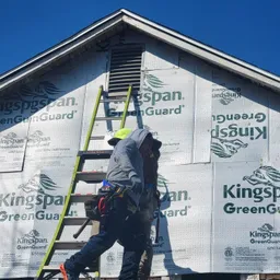 Two installers by a gable wall wrapped in siding underlayment, ready for new siding